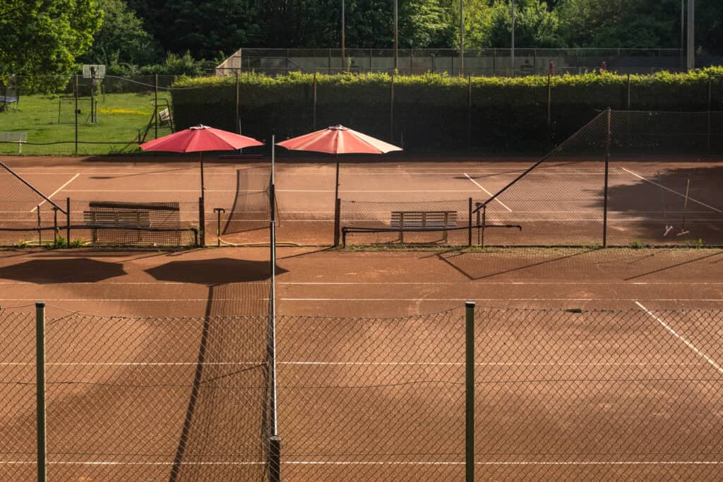 Blick auf einen Tennisplatz mit einem grünen Bereich im Hintergrund und an der Seite