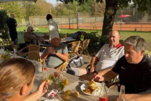 Spielerinnen und Spieler genießen beim Kartoffelcup 2026 Kartoffelgerichte im Schatten der Bäume auf der Terrasse