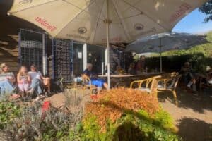 Gäste des Kartoffelcups 2026 sitzen unter Sonnenschirmen an der Terrasse des Vereinshauses des TC Forstwald